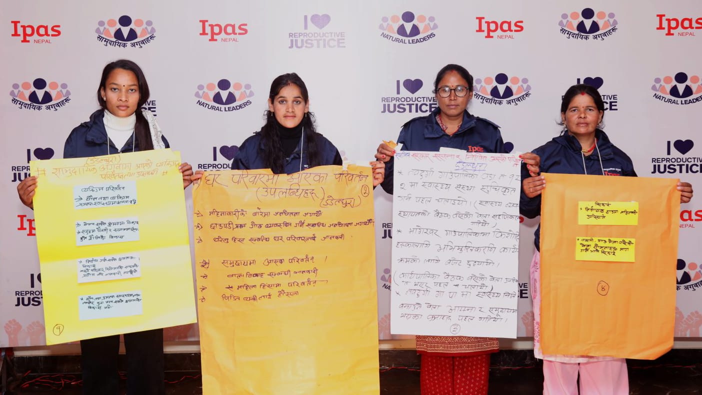 Four women holding sheets of paper